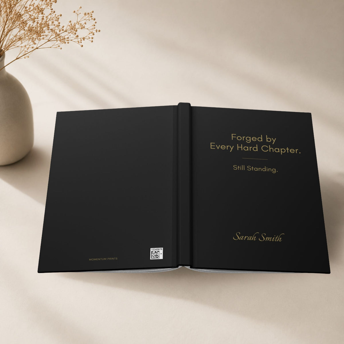 Open black hardcover journal displaying the personalized front cover in a clean minimalist setting with soft natural light. Momentum Prints.
