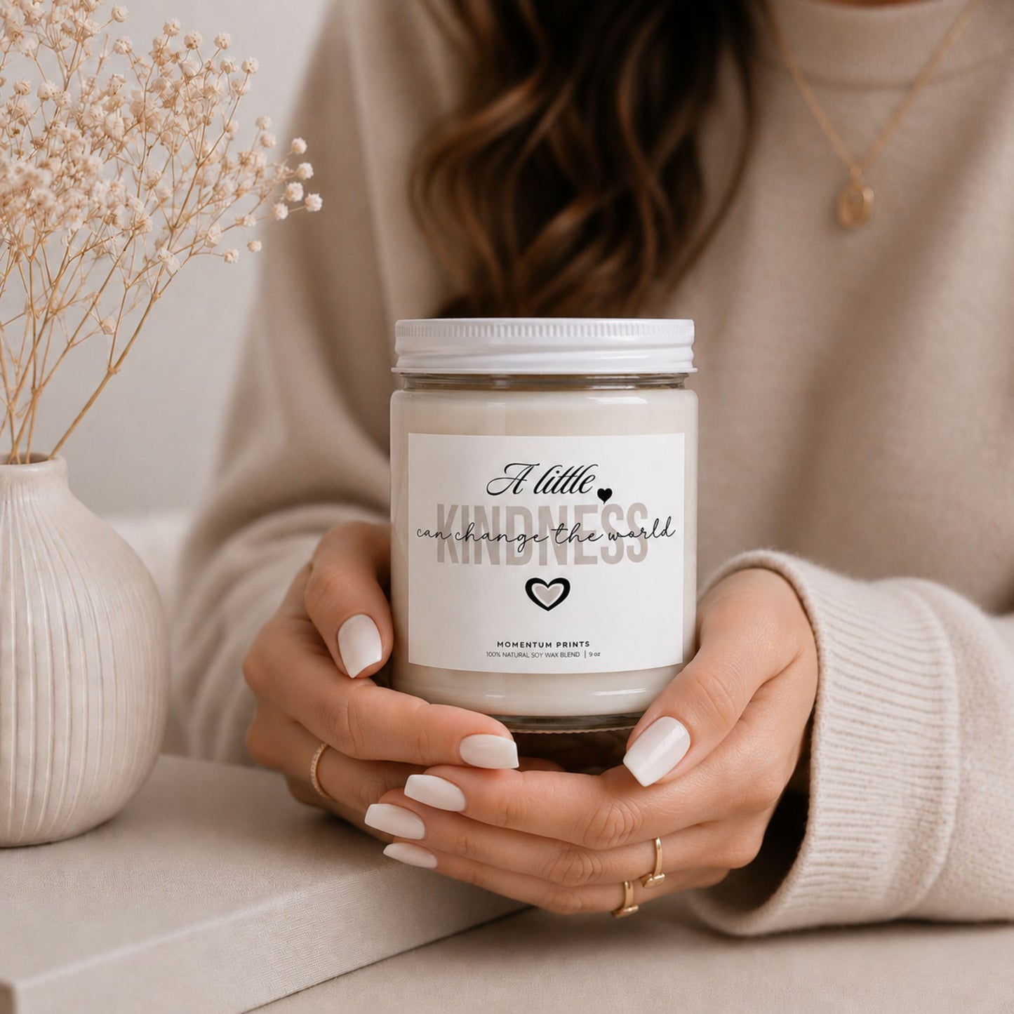 Woman holding the A Little Kindness Can Change the World scented soy candle by Momentum Prints in a warm minimalist lifestyle setting.