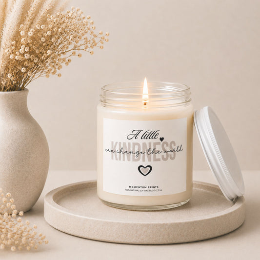 A Little Kindness Can Change the World soy candle by Momentum Prints burning softly beside dried flowers in a warm minimalist self-care and home decor setting.