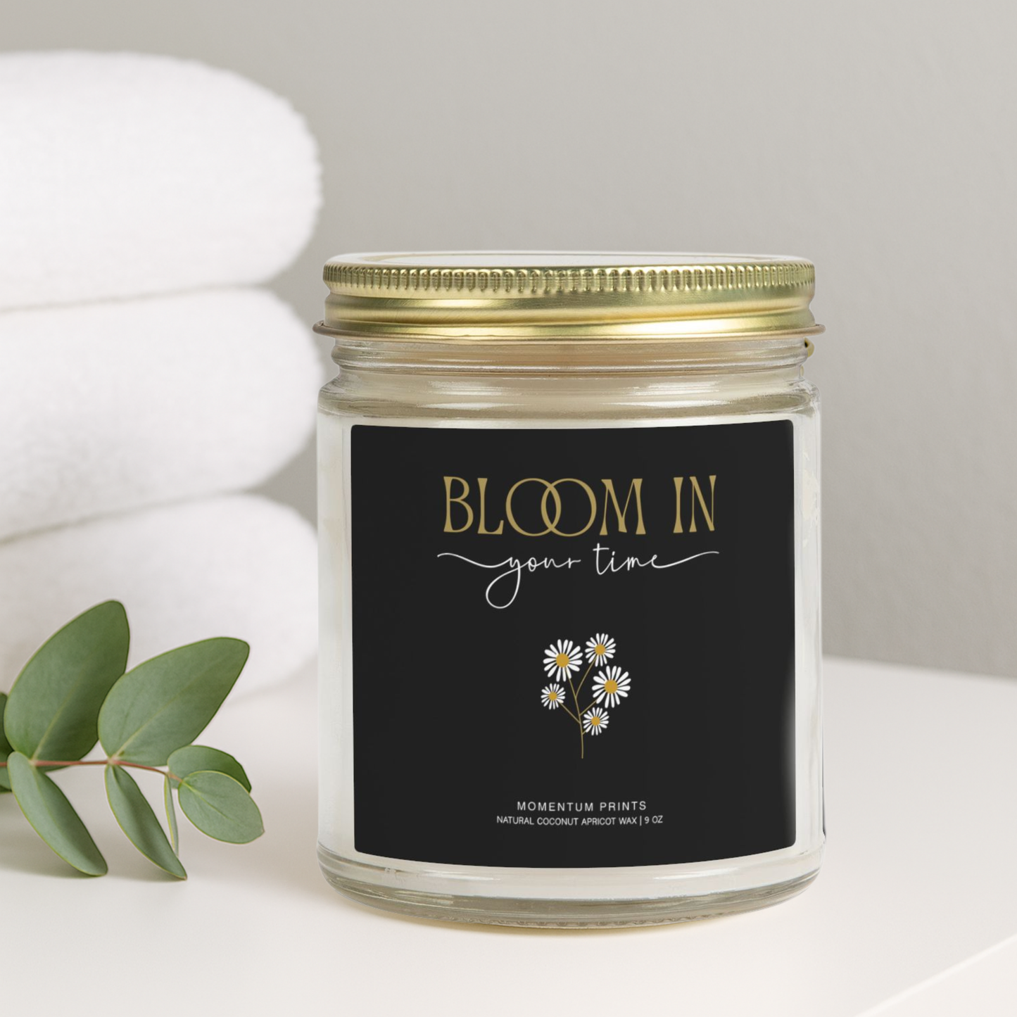 Bloom in Your Time” daisy-design soy candle by Momentum Prints on spa towel background — cozy minimalist lifestyle photo