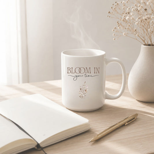 Bloom In Your Time motivational mug beside an open journal and gold pen on a light wood desk, styled with soft morning light, gentle steam, and dried flowers in a cozy minimalist setting.