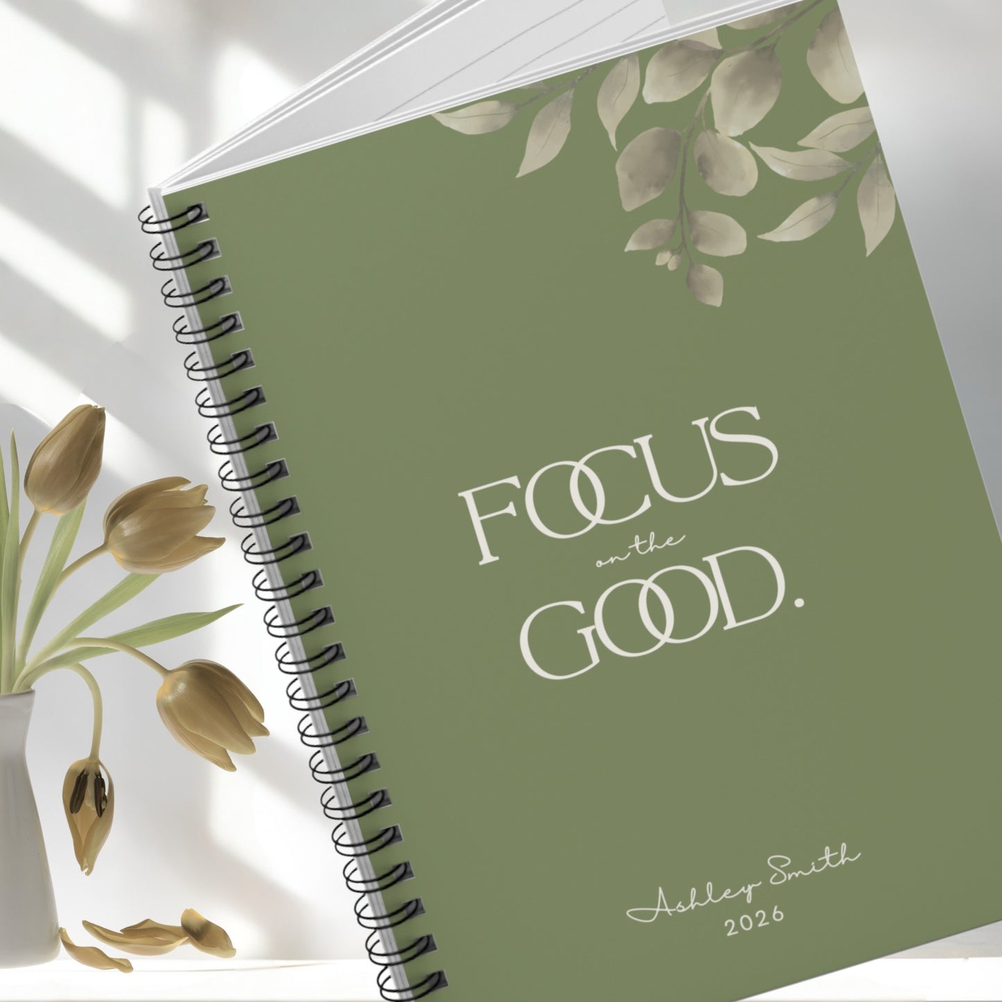 Olive green motivational spiral notebook styled with soft florals, elegant minimal workspace aesthetic.