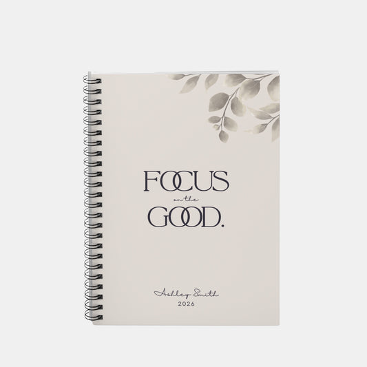 Personalized “Focus on the Good” spiral notebook in soft beige with minimalist botanical detail and refined typography