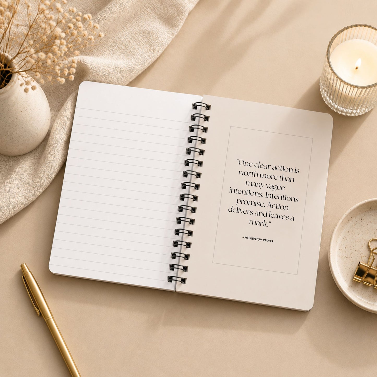 The open interior of a personalized soft beige spiral notebook, showing a blank lined page beside a printed message about taking clear action, styled with a lit glass candle, dried baby's breath on draped linen, and a gold pen.