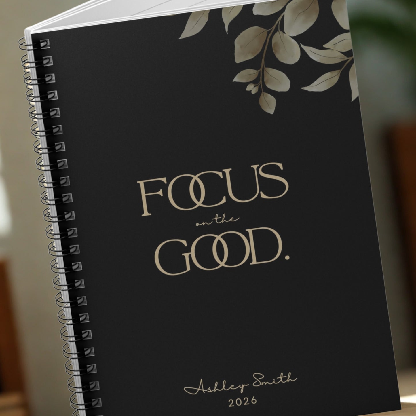 Close-up of the Momentum Prints “Focus on the Good” notebook cover in Midnight Black showing premium typography and botanical detail.