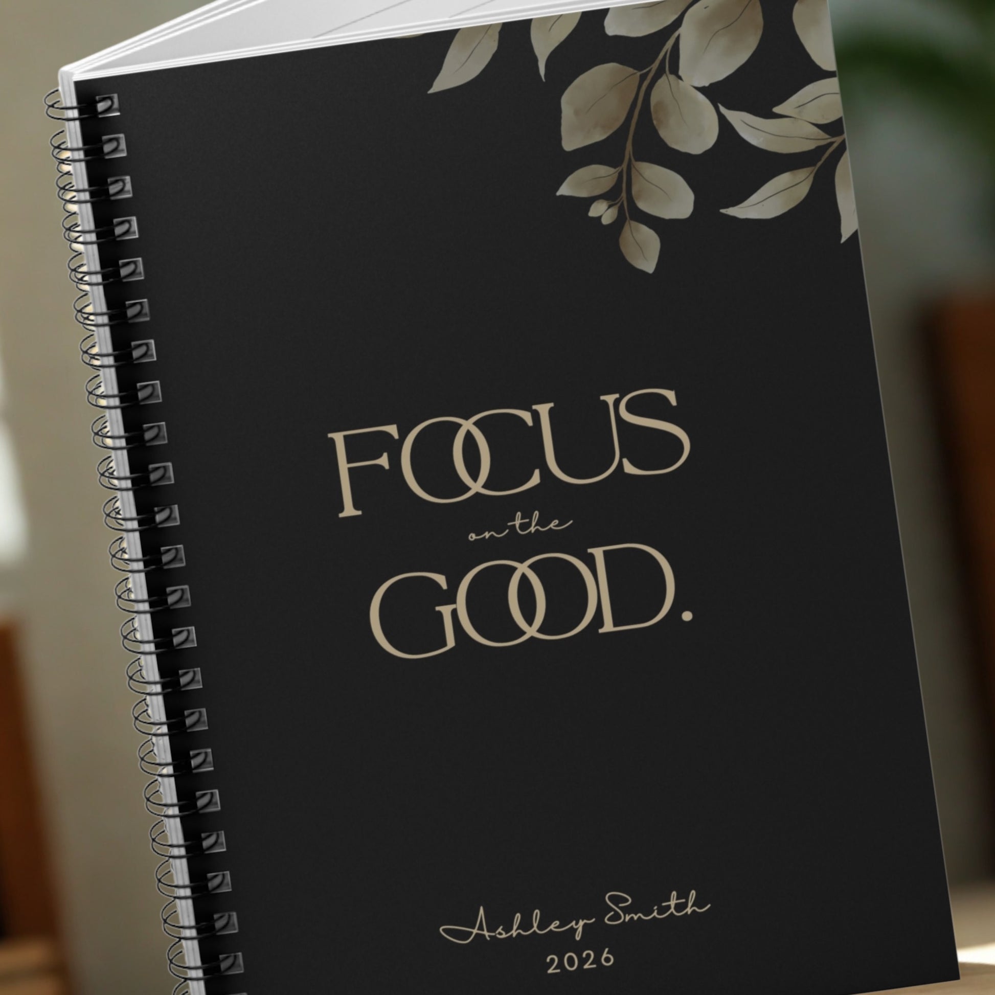 Close-up of the Momentum Prints “Focus on the Good” notebook cover in Midnight Black showing premium typography and botanical detail.