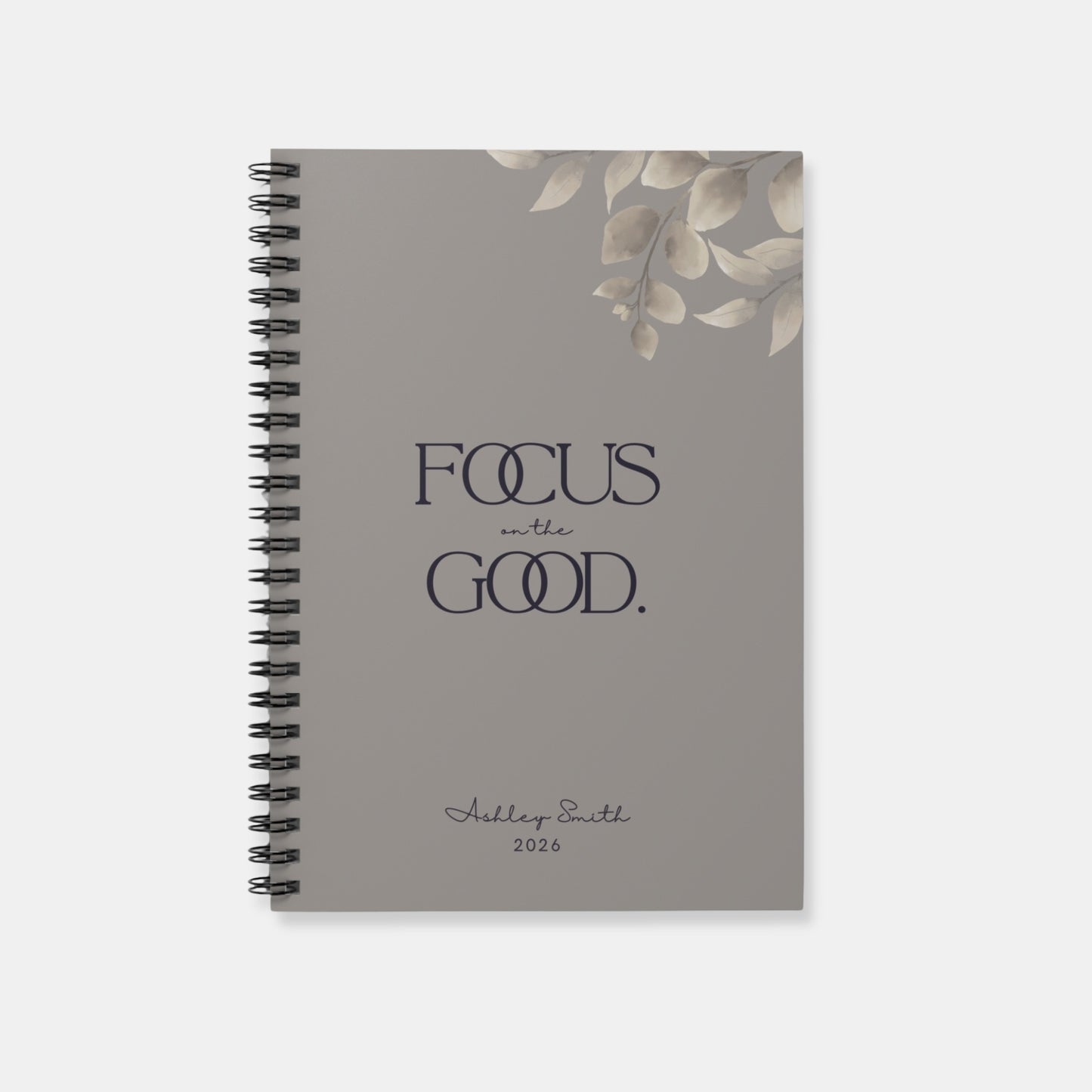 Personalized “Focus on the Good” spiral notebook in warm gray with minimalist botanical detail and refined typography.