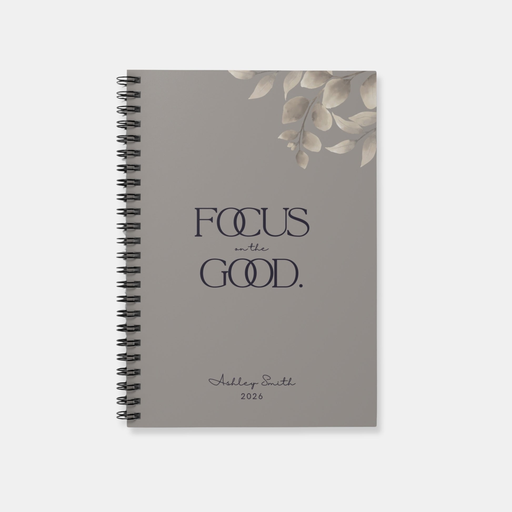 Personalized “Focus on the Good” spiral notebook in warm gray with minimalist botanical detail and refined typography.