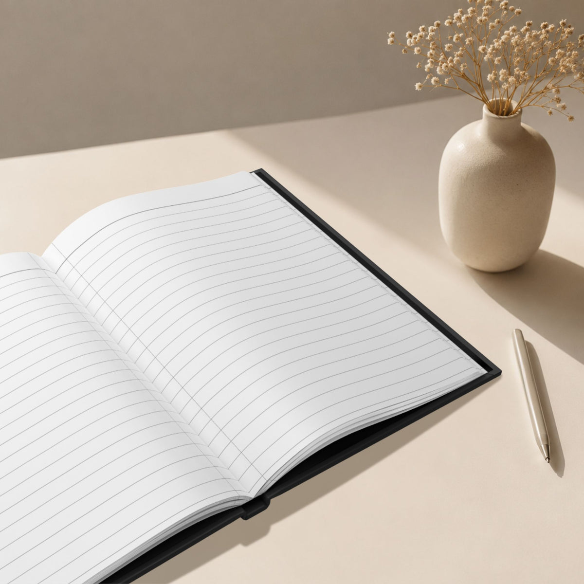 Open hardcover journal showing lined interior pages beside a ceramic vase and gold pen in a calm neutral workspace.