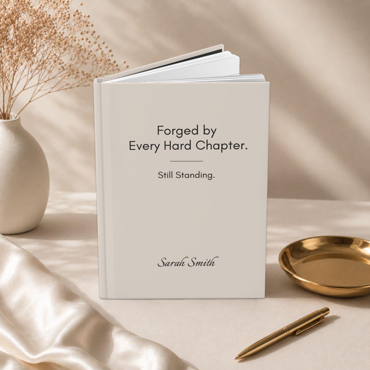 An open ivory hardcover journal with a personalized name, displayed beside dried flowers and a gold dish in a warm editorial setting by Momentum Prints.