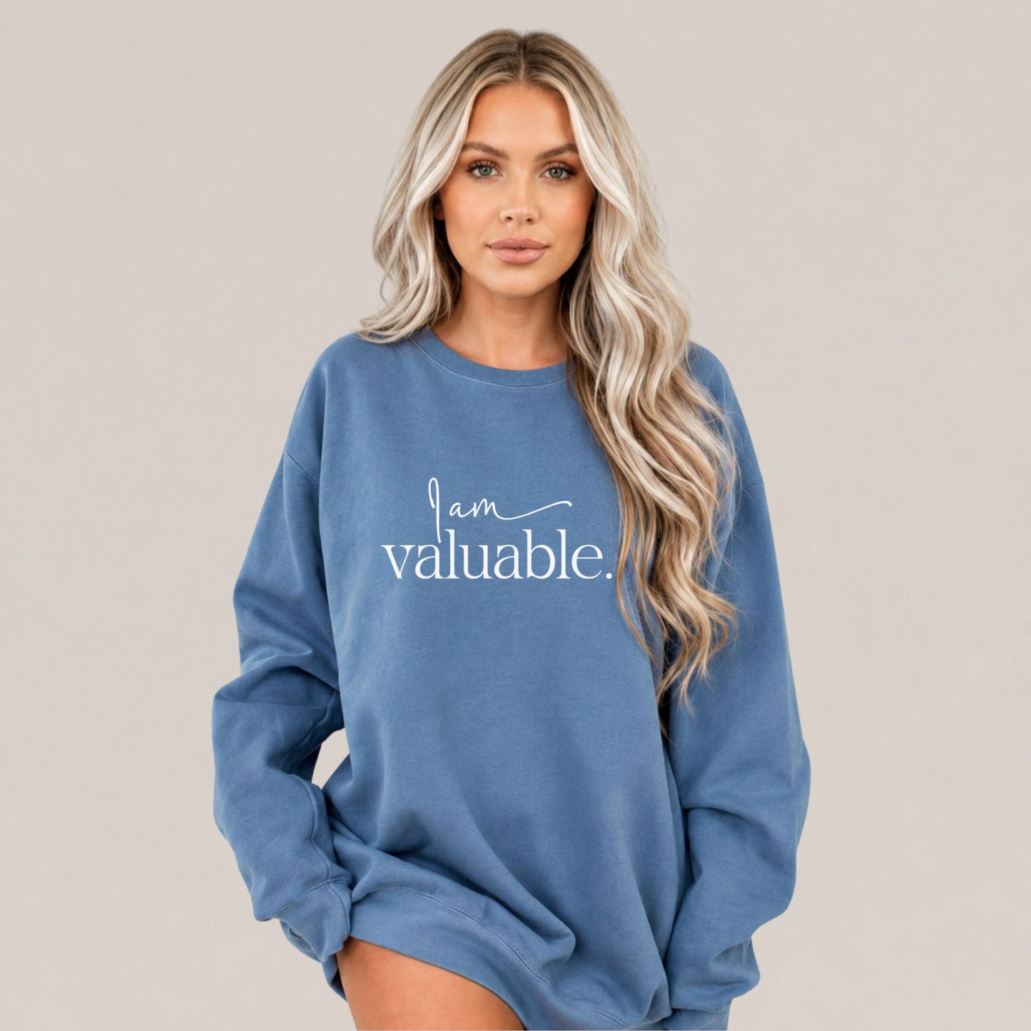 Woman wearing a Blue Jeans oversized sweatshirt featuring the phrase I Am Valuable, photographed in a minimalist studio setting by Momentum Prints.
