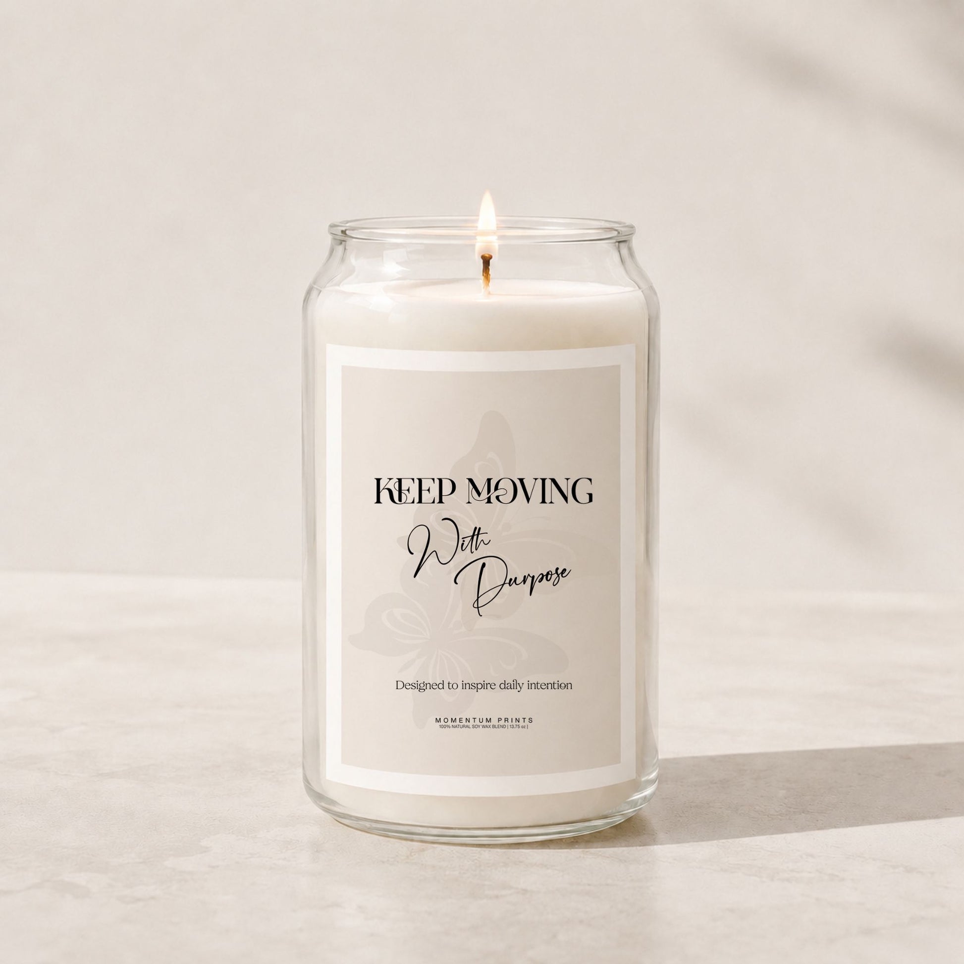 Minimalist luxury soy candle in a clear glass jar with a soft beige label reading “Keep Moving With Purpose,” styled on a light stone surface with warm natural lighting and a clean neutral background.