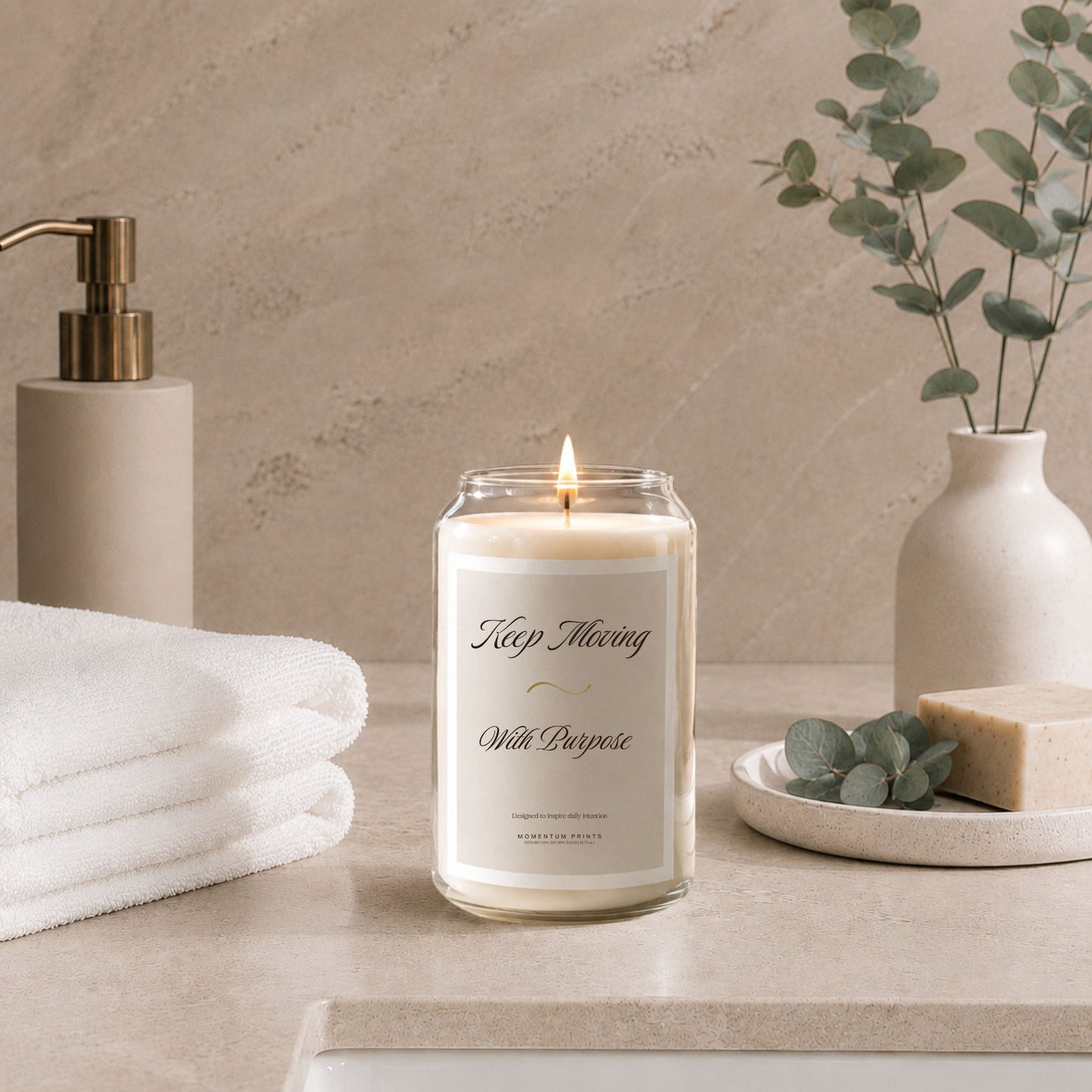 Luxury soy candle with “Keep Moving With Purpose” label styled in a minimalist spa bathroom setting with folded white towels, eucalyptus stems, natural soap, and soft beige stone textures under warm ambient lighting.