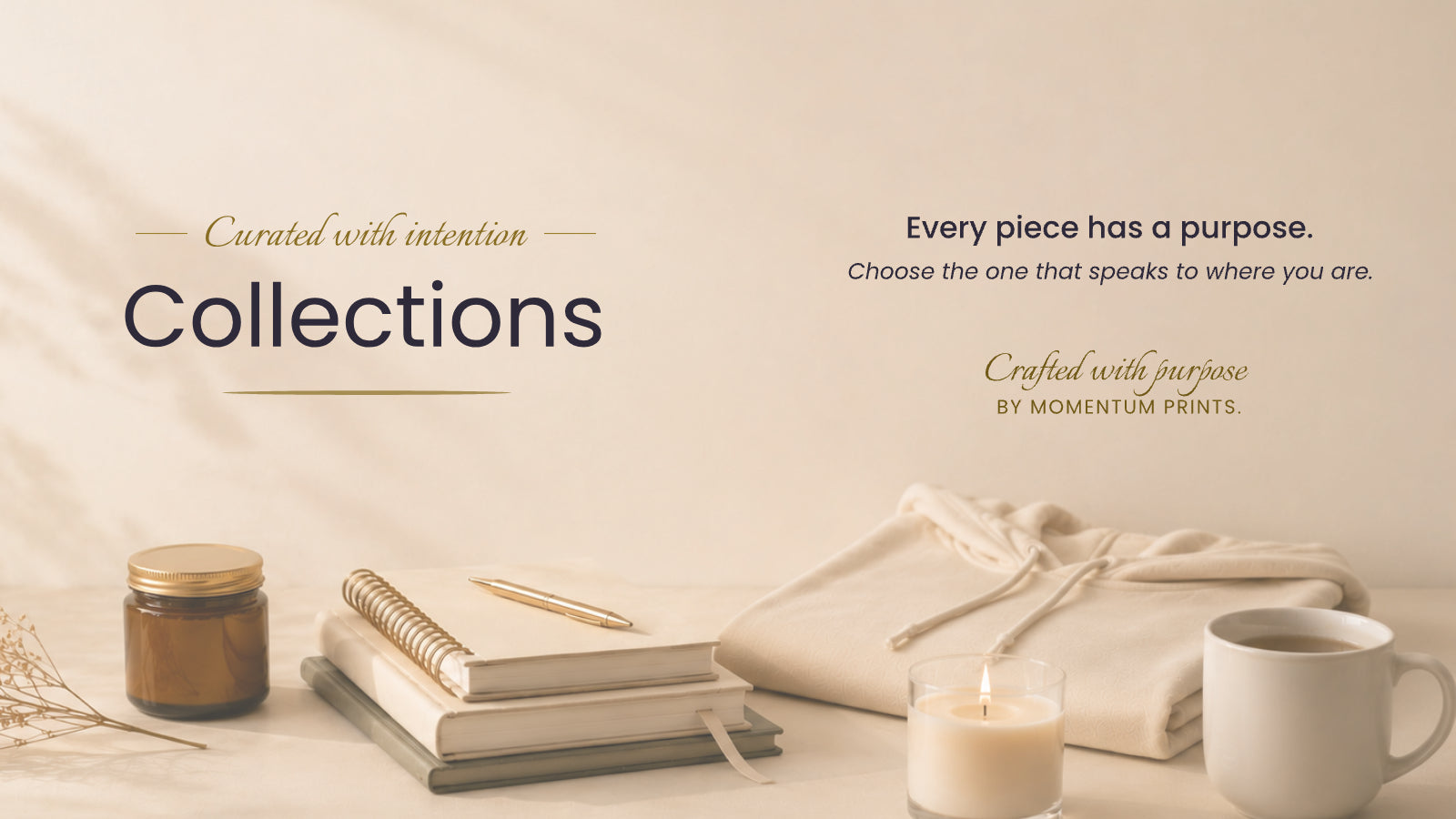 Minimal collection hero banner with a ceramic mug, journal, amber candle, and cozy hoodie in a premium lifestyle setting by Momentum Prints.
