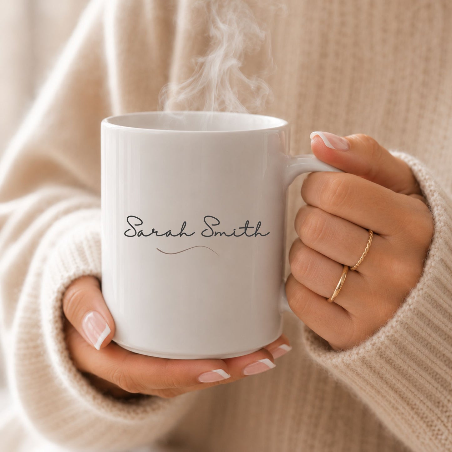 Personalized white ceramic mug with custom name design held in both hands, styled with a cozy beige sweater and soft natural lighting.