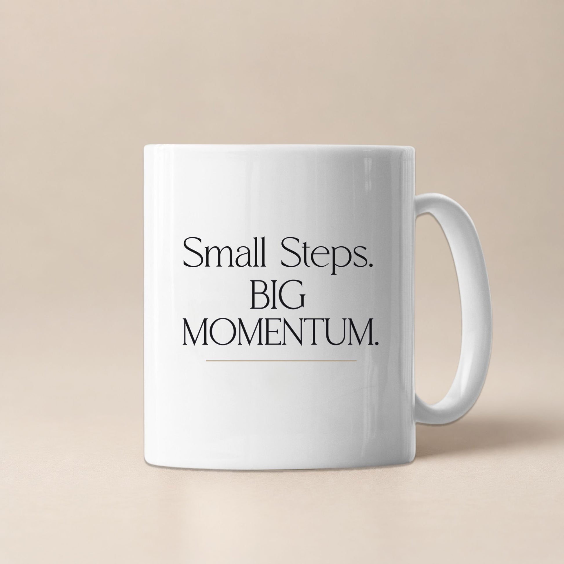White ceramic mug displaying the Small Steps. BIG MOMENTUM. design against a soft beige background.