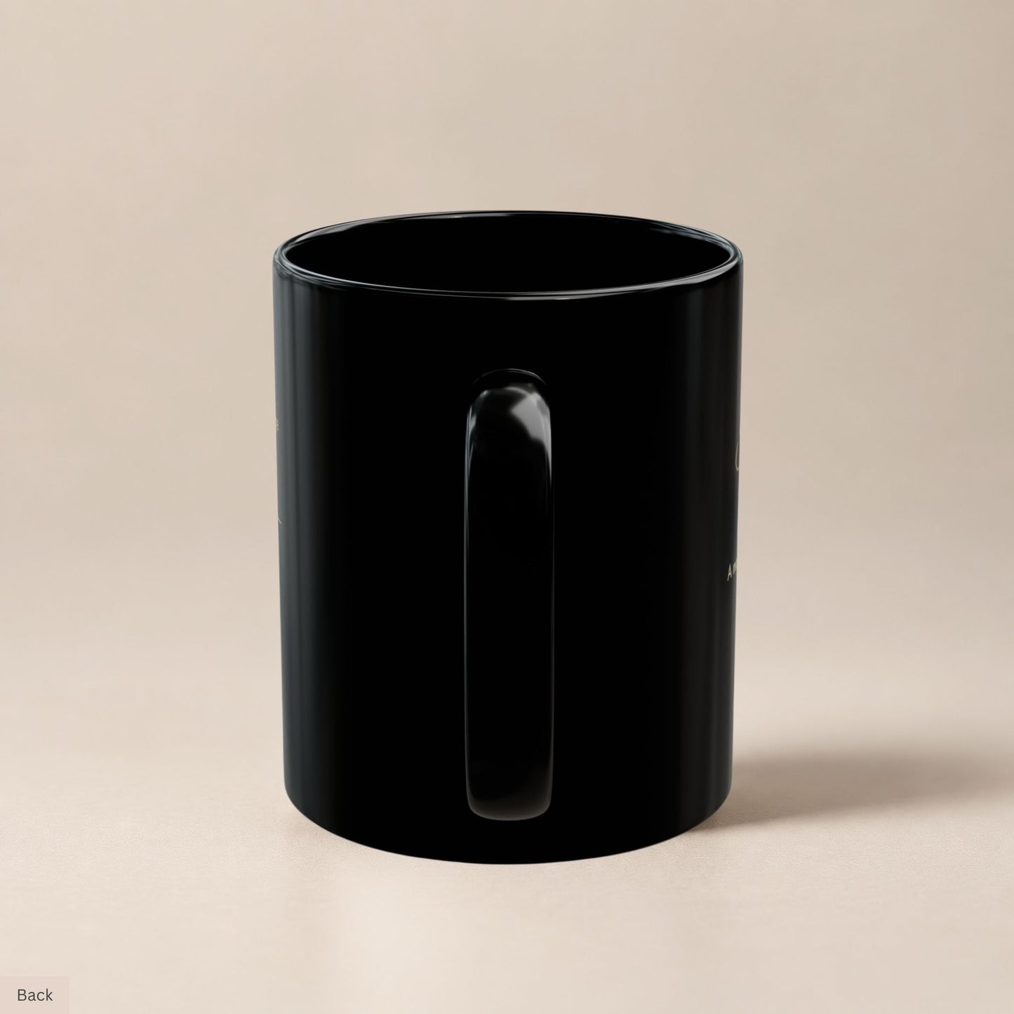 Rear view of a black ceramic mug highlighting its sturdy handle and glossy finish, with faint gold text visible along the curved edges by Momentum Prints.