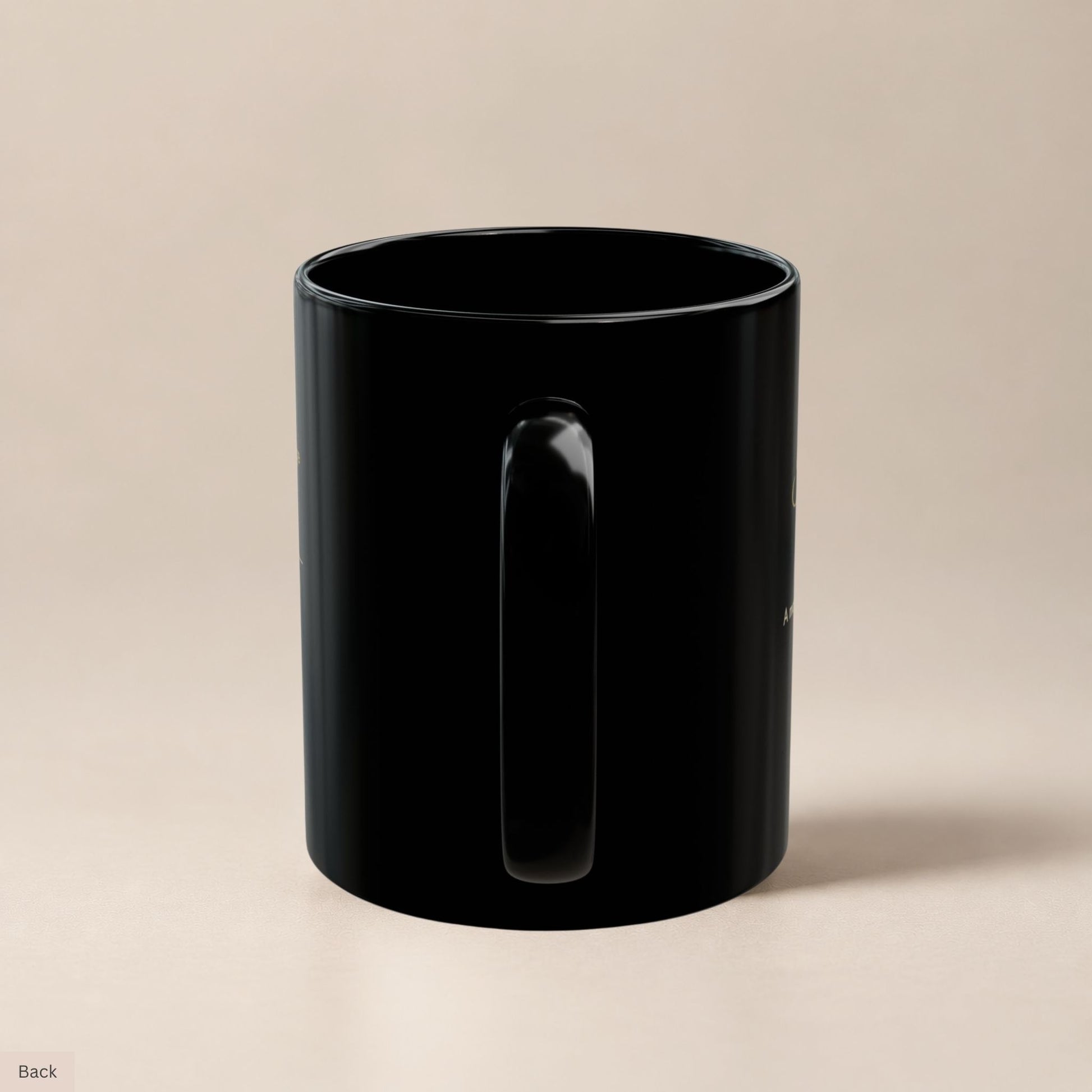 Rear view of a black ceramic mug highlighting its sturdy handle and glossy finish, with faint gold text visible along the curved edges by Momentum Prints.