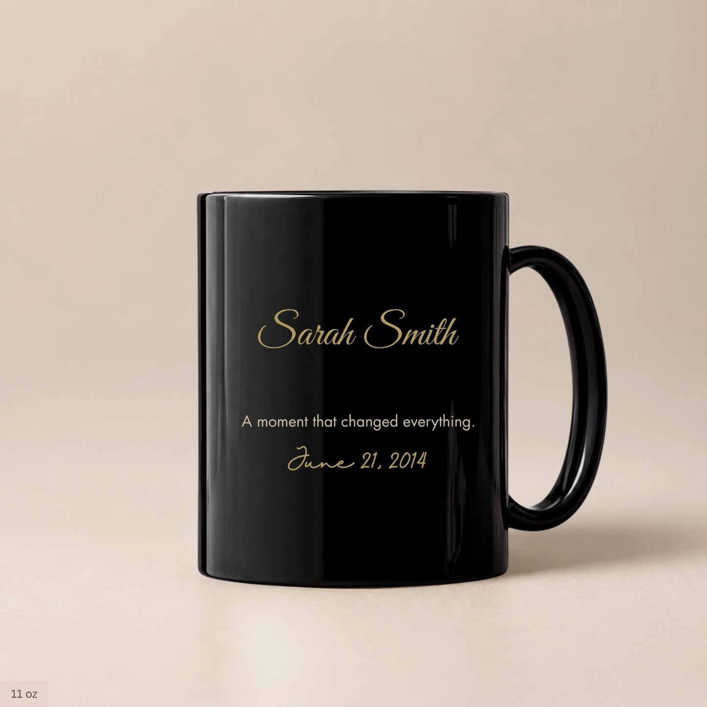 Personalized black ceramic coffee mug with gold cursive name and a cream inscription marking a life changing date, photographed against a warm neutral background by Momentum Prints.