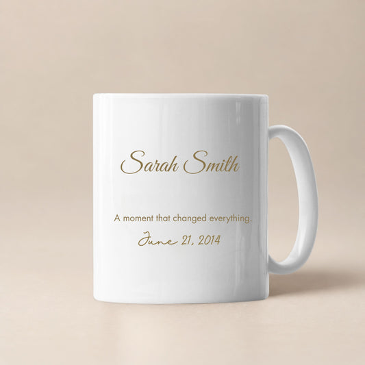 Personalized white ceramic mug with custom name, meaningful date and sentimental message in gold lettering, minimalist beige background, elegant keepsake gift for special occasions.