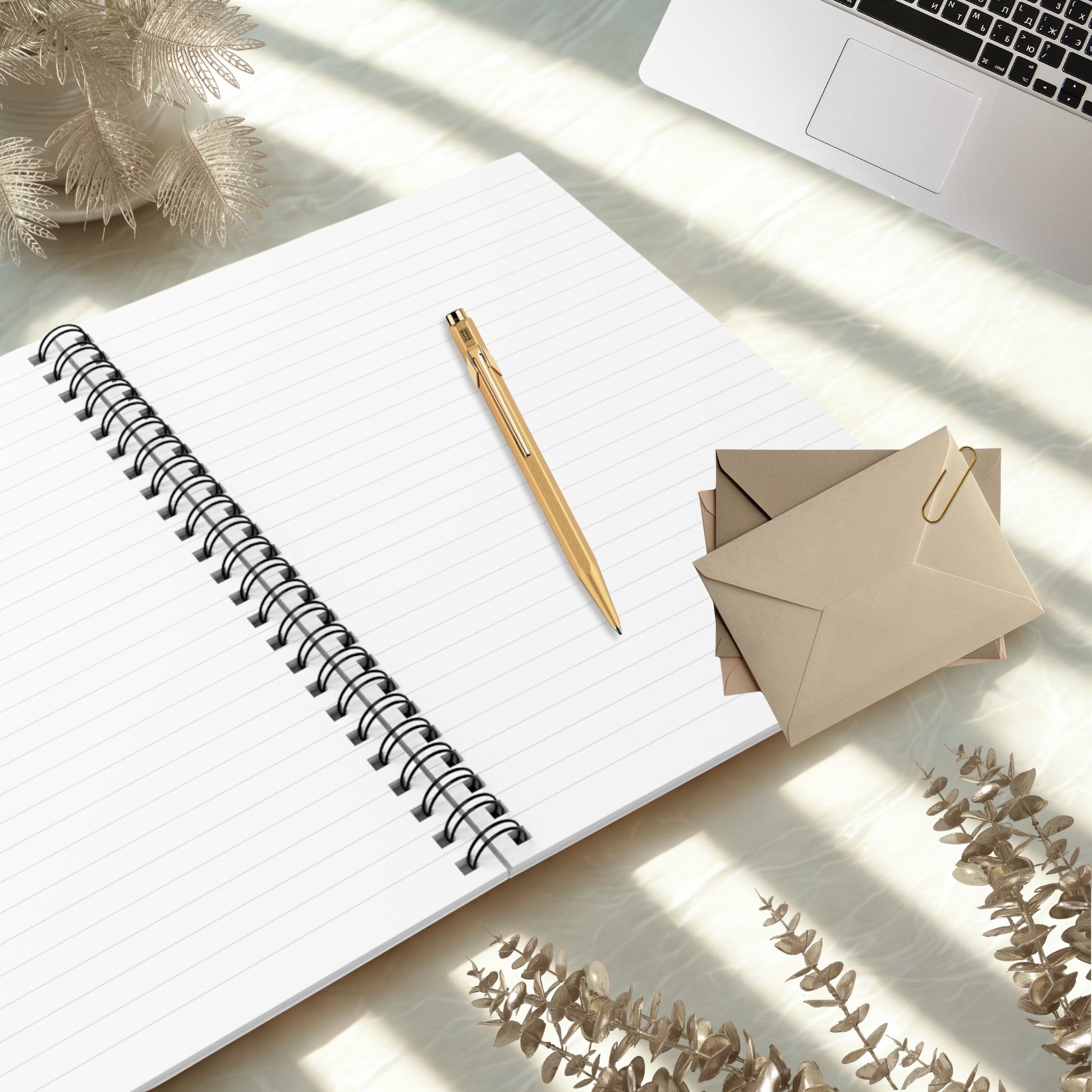 Open lined pages of a 6x8 spiral notebook with a gold pen on a bright desk, styled in a minimal cozy workspace aesthetic by Momentum Prints.