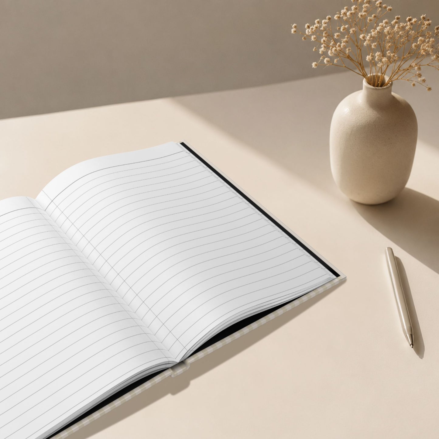 Open hardcover journal with lined writing pages, beige striped cover, ceramic vase and pen in a clean minimalist editorial lifestyle setting by Momentum Prints.
