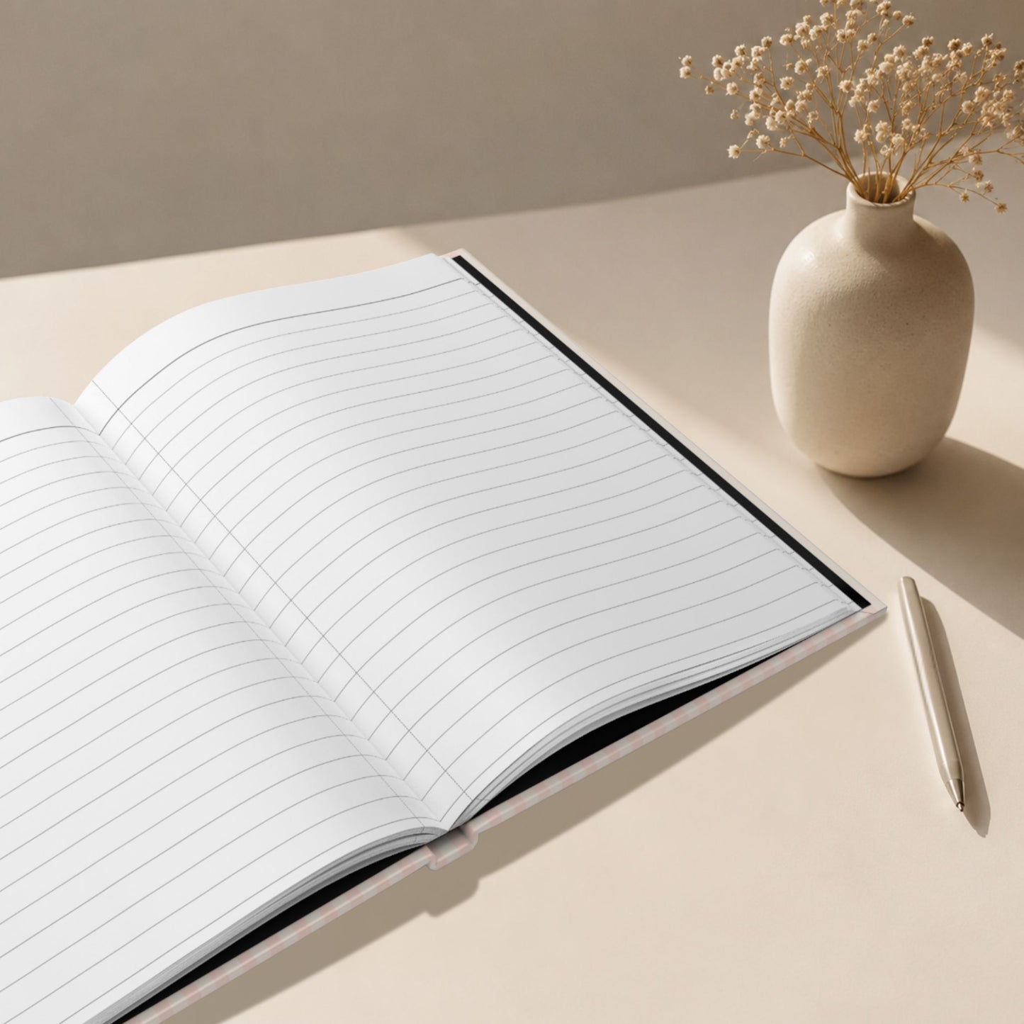 Interior view of ruled lined pages inside a personalized dusty rose striped hardcover journal, styled beside a ceramic vase with dried flowers and a matte pen in a soft editorial lifestyle setting by Momentum Prints.