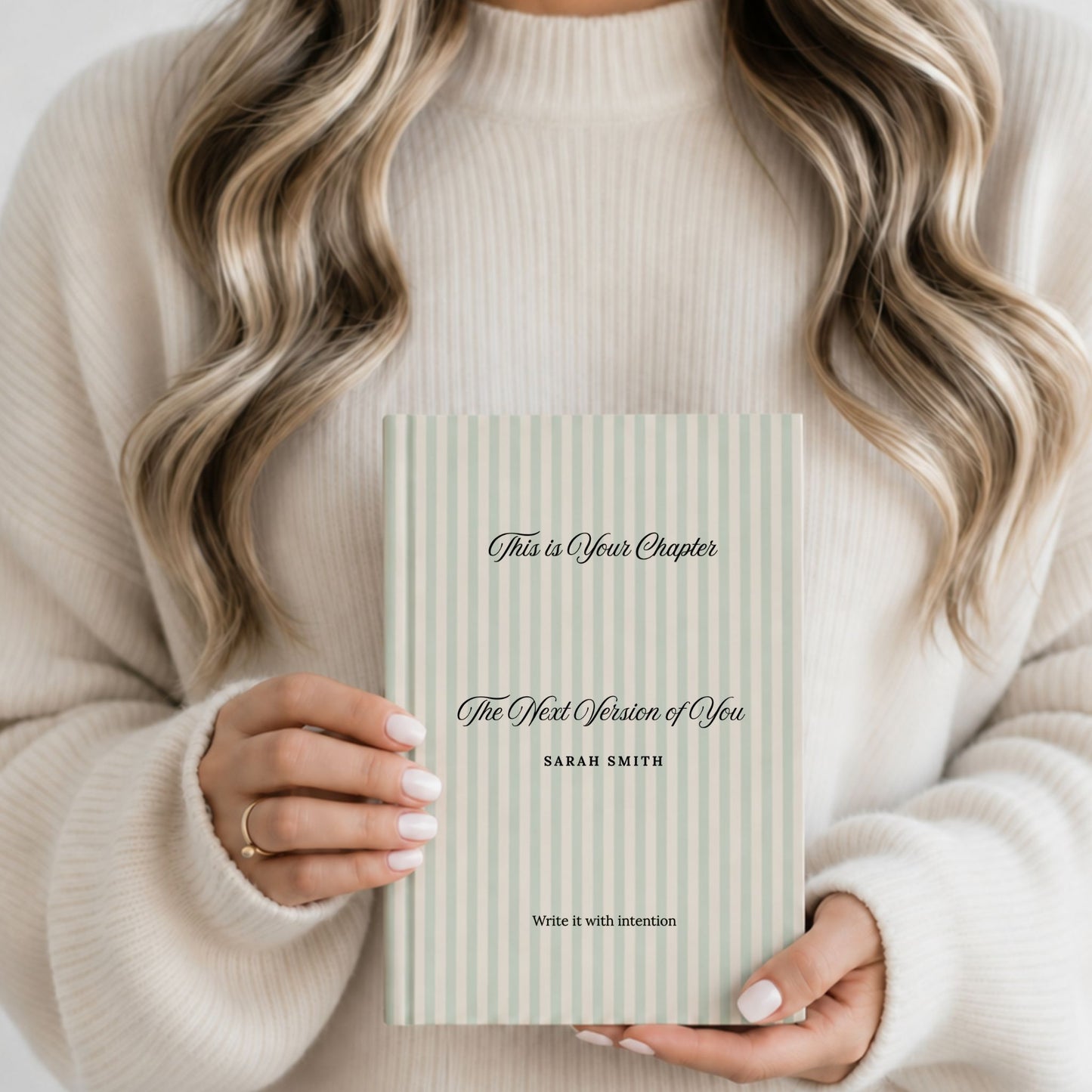 Premium personalized hardcover journal with sage green striped cover held close in hand, styled against a cozy cream knit sweater in a warm lifestyle setting by Momentum Prints.