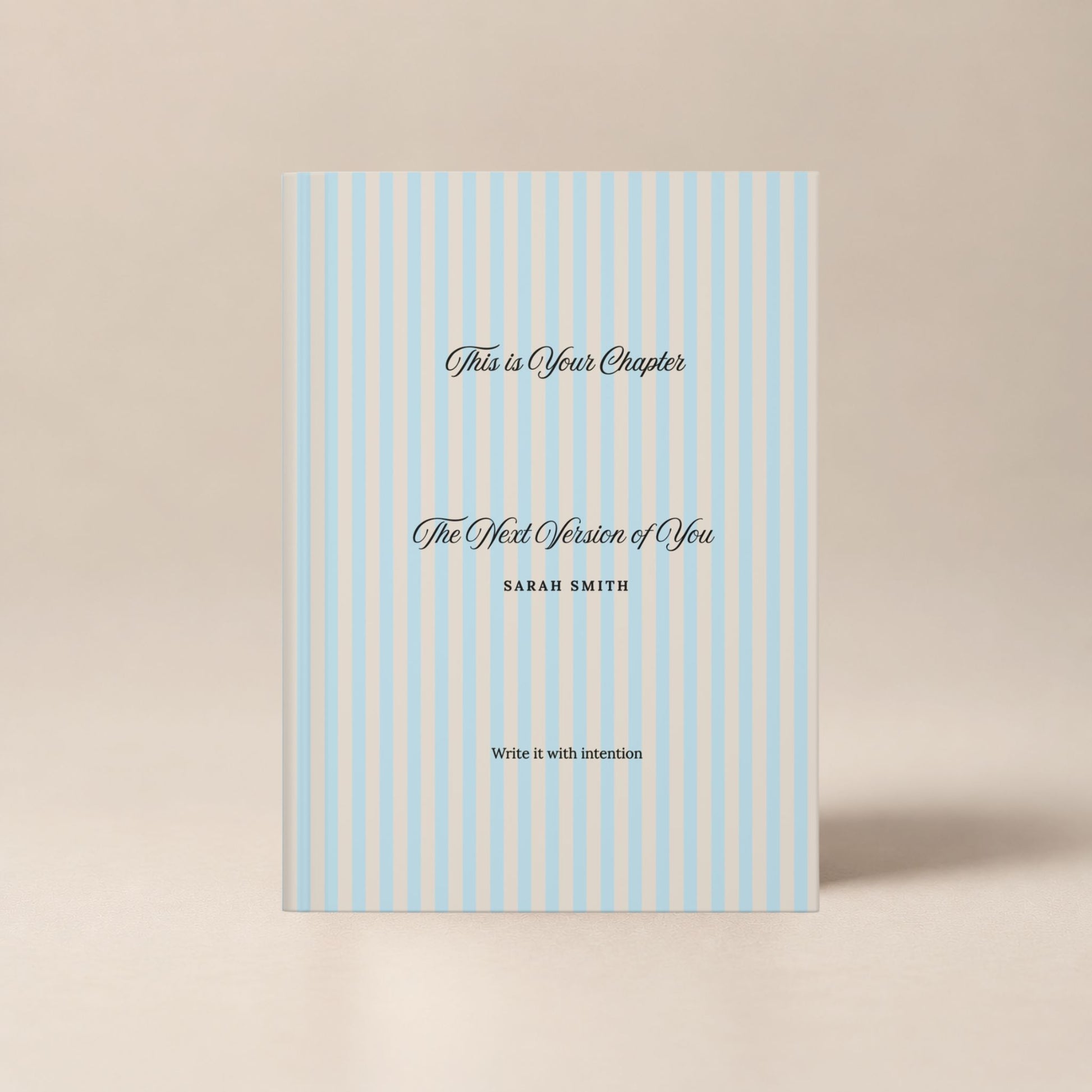 Premium personalized hardcover journal with a sky blue striped cover and black script lettering, shown standing upright on a soft beige background by Momentum Prints.