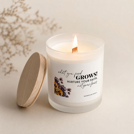 Lit frosted glass candle with wooden wick and “What You Feed Grows” label, styled in a warm cozy neutral setting with soft natural light by Momentum Prints.